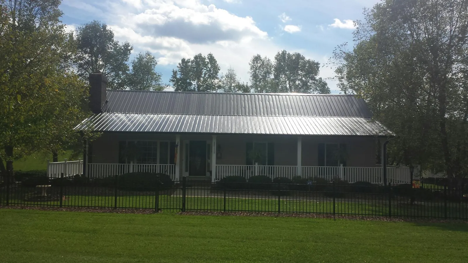 Gray metal roof on a brick ranch with a full width front porch — Gutter Guard Installation work by our crew in Westminster