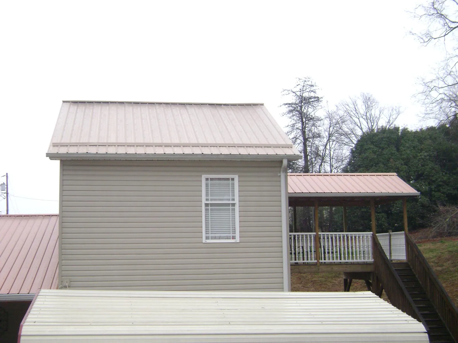 Tan metal roofs on a two story addition and attached porch, from a Roof Replacement job in Westminster